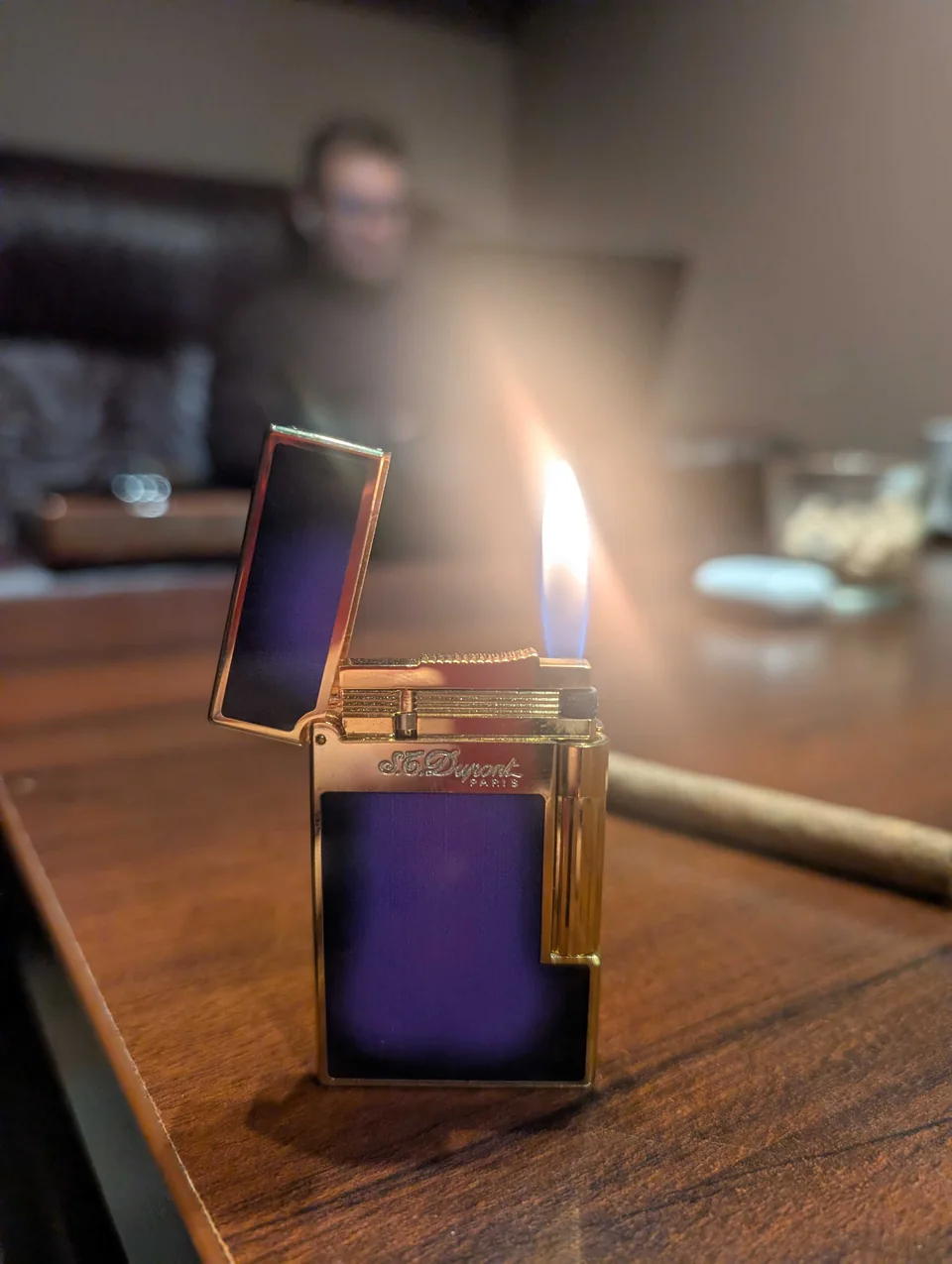 A lit gold lighter beside a cigar on a lounge table, from Anatolie's photos